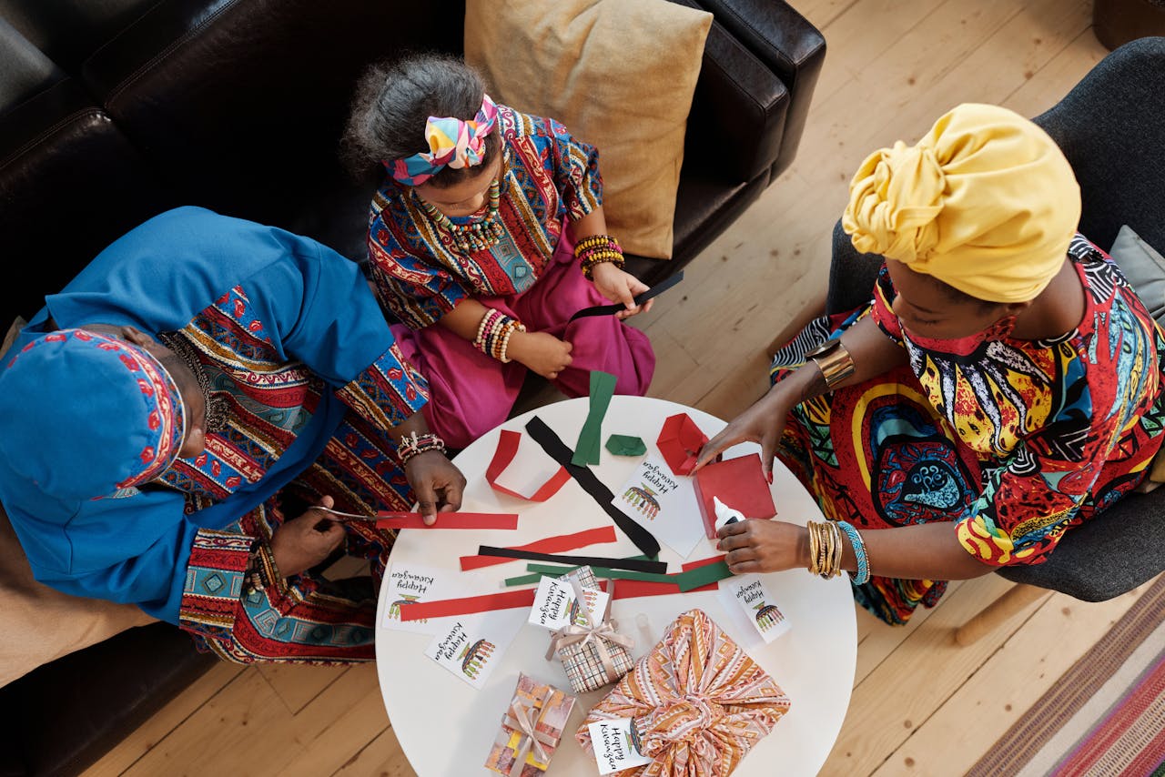 faq-img A joyful family making crafts for Kwanzaa, dressed in colorful traditional clothes.